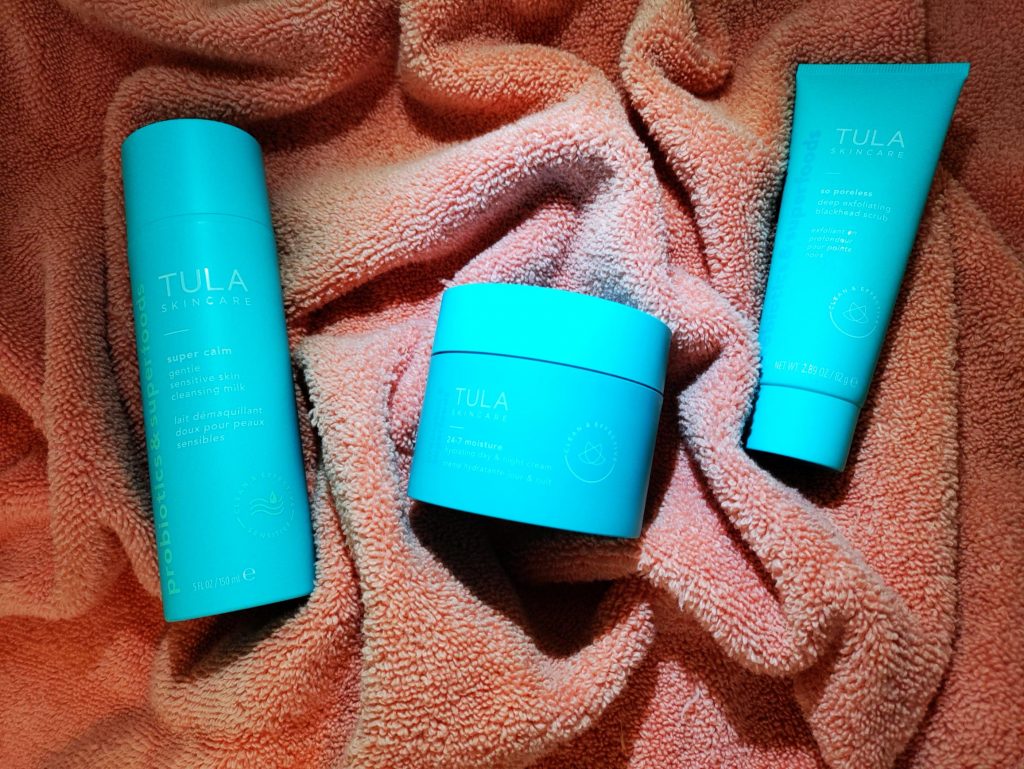 Tula skincare in teal bottles laying on a coral colored towel