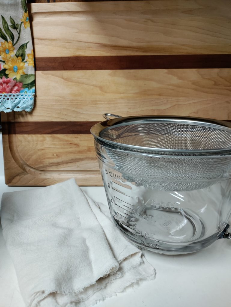 glass mixing bowl with mesh sieve and cheesecloth
