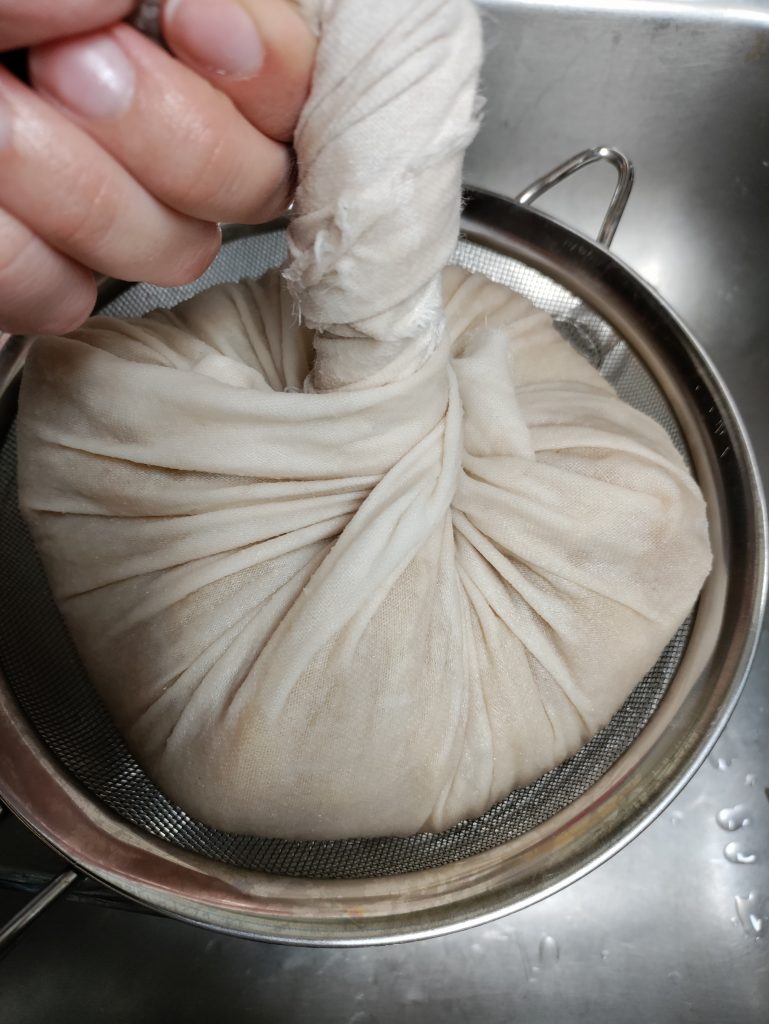 cheesecloth full of apples being squeezed to remove juice